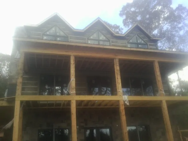 Dormers and porch framing on a large log home under construction — Roof Coating work by our crew in Severance