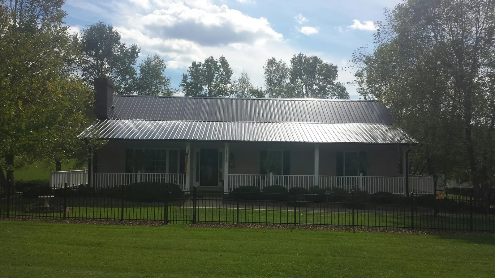 Gray metal roof on a brick ranch with a full width front porch — Gutter Guard Installation work by our crew in Severance