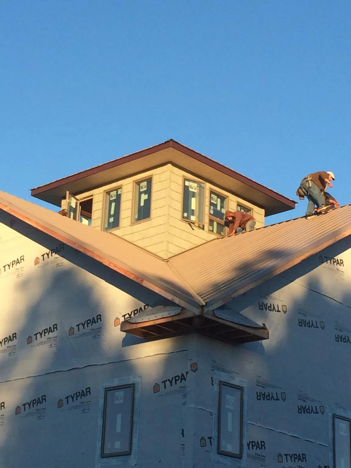 Roofers working around a rooftop cupola on a new metal roof at sunset — Roof Waterproofing in Severance by Roofing Brothers
